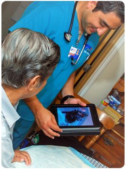 A First Aide Home Care nurse reviewing health information on a tablet with an elderly patient at home